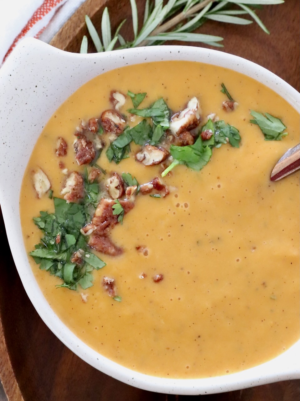 sweet potato soup in a bowl topped with chopped pecans and parsley