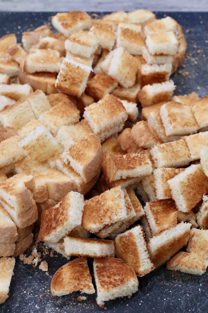 toasted cubes of bread on a cutting board