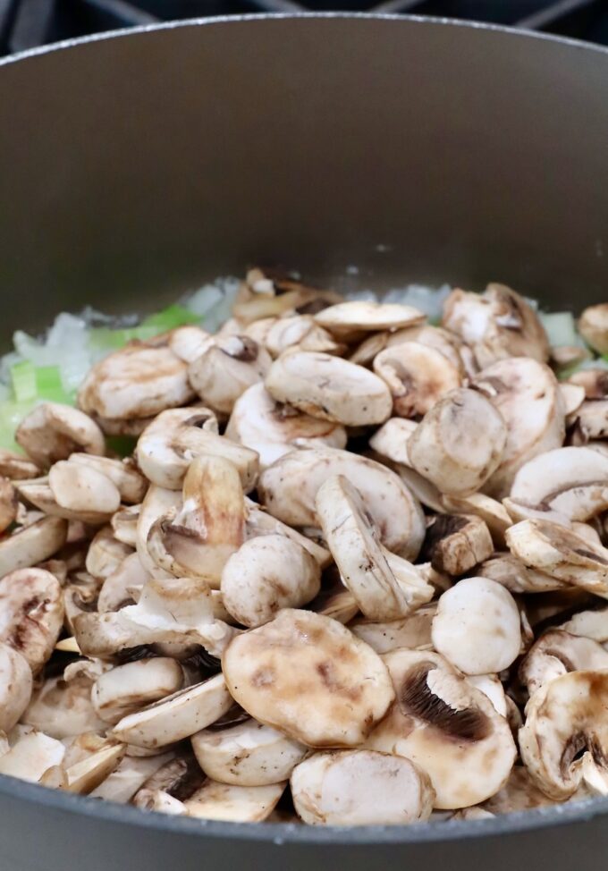 diced onions and celery with sliced mushrooms in a large pot