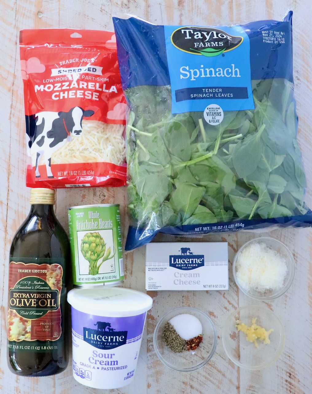 ingredients for spinach artichoke dip on a white wood board