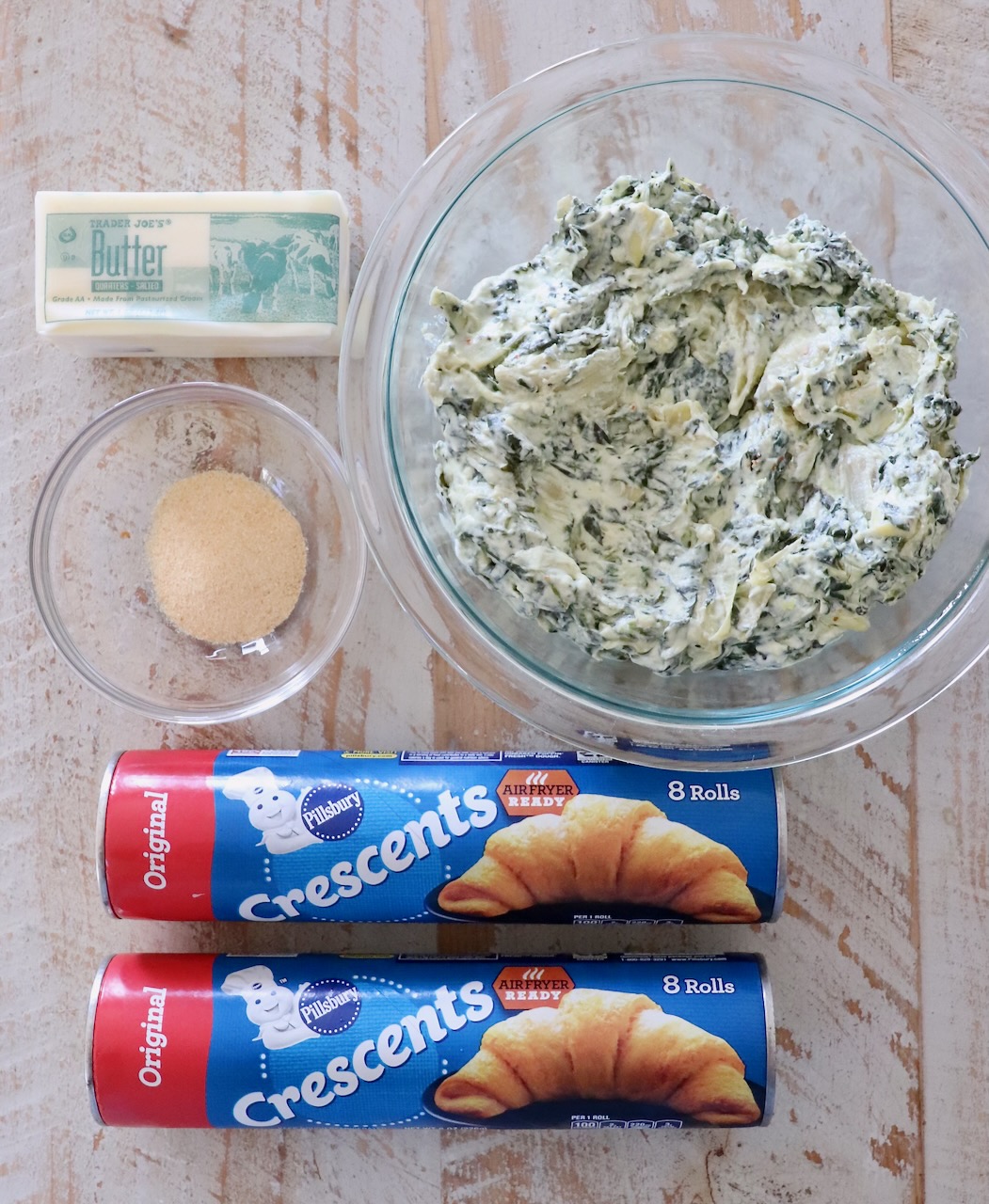 ingredients for spinach pinwheels on a white wood board