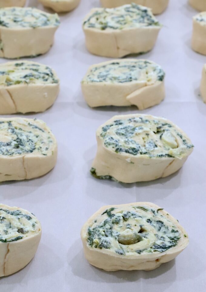 spinach pinwheels uncooked on a baking sheet