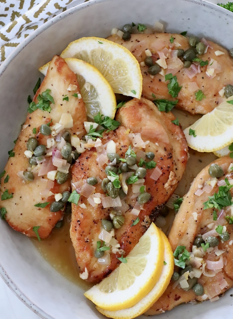 cooked pieces of chicken in a bowl with lemon piccata sauce