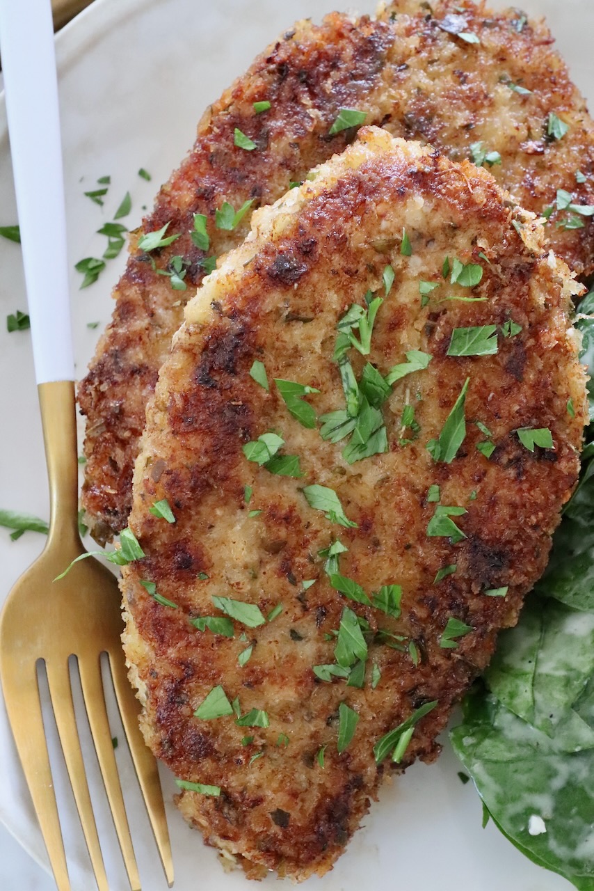 breaded cooked pork chops on a plate with a fork