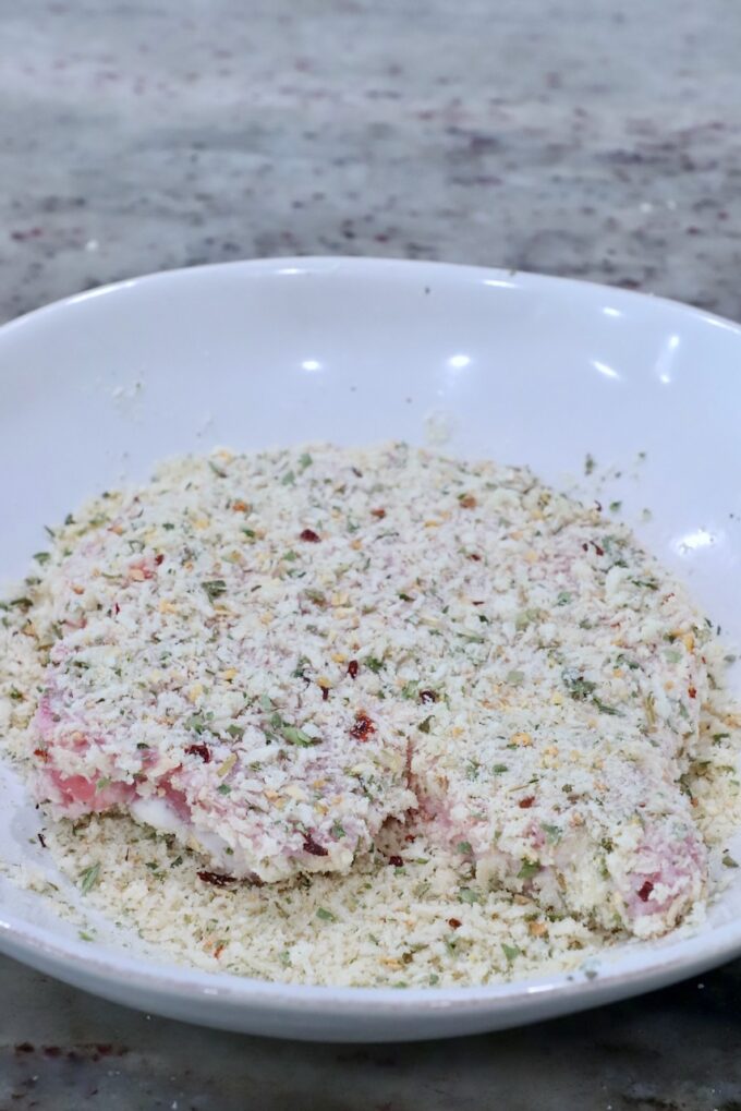 pork chop coated in seasoned breadcrumbs in a bowl