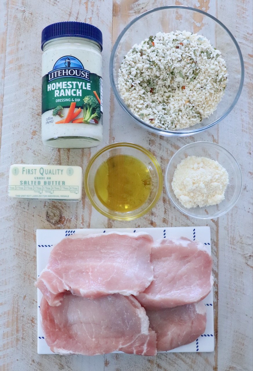 ingredients for breaded pork chops on a white wood board