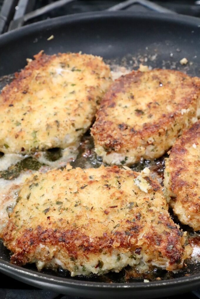 breaded pork chops cooking in a skillet