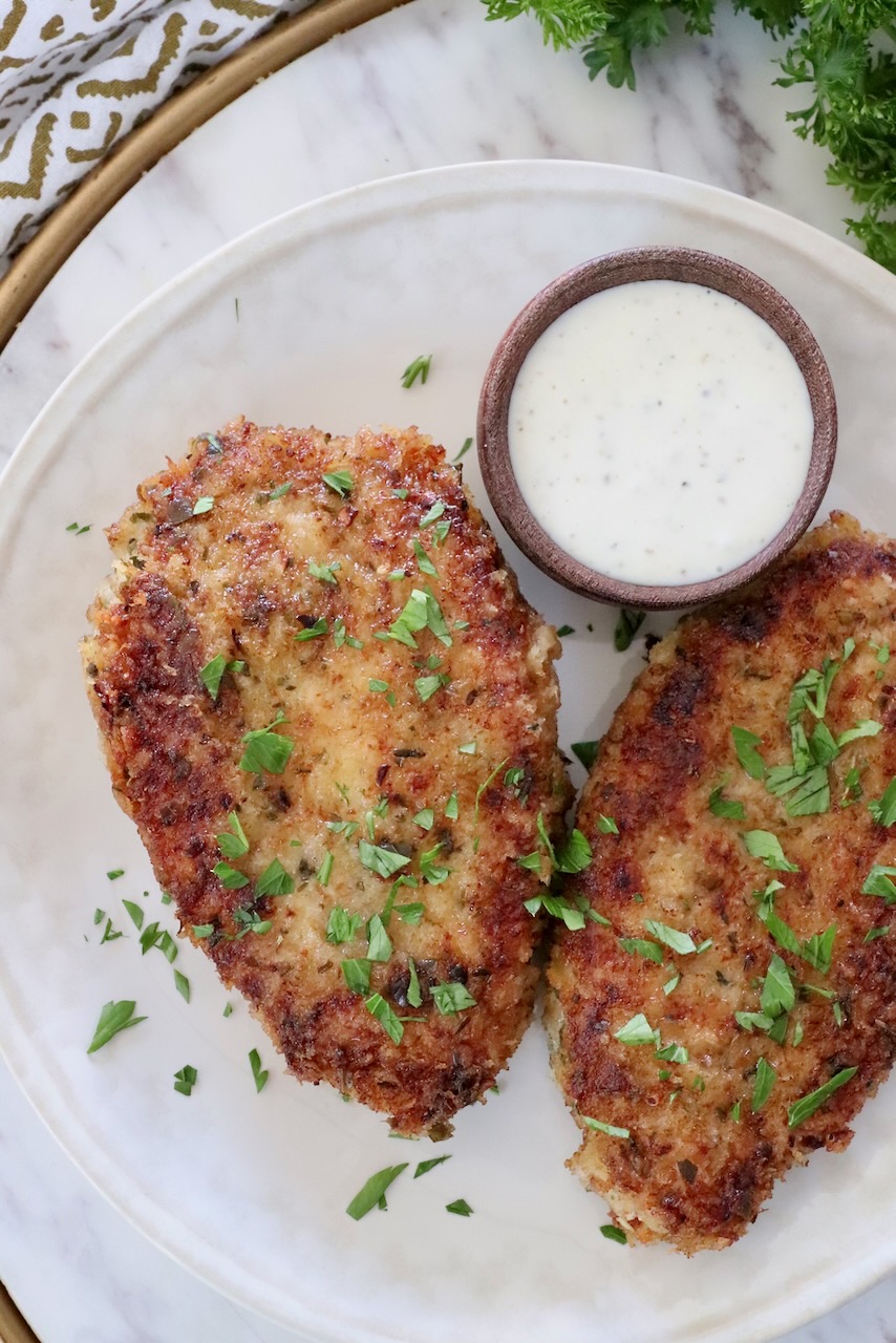 fried breaded pork chops on a plate with a small bowl of ranch dressing