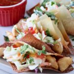 wonton taco shells filled with cooked chicken and coleslaw on a plate