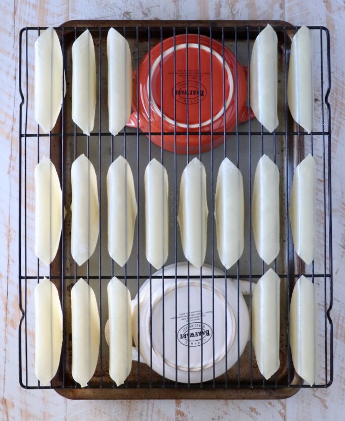 wonton wrappers folder over a wire rack, on top of two bowls on a baking sheet