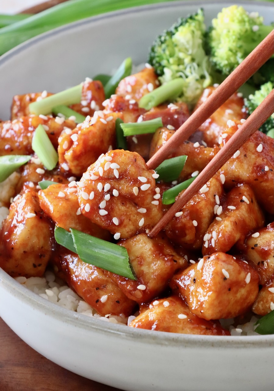 gochujang chicken in bowl with broccoli and chopsticks