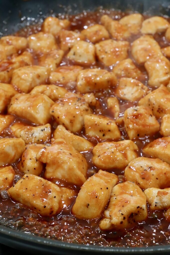 cooked pieces of chicken covered in gochujang sauce in a skillet