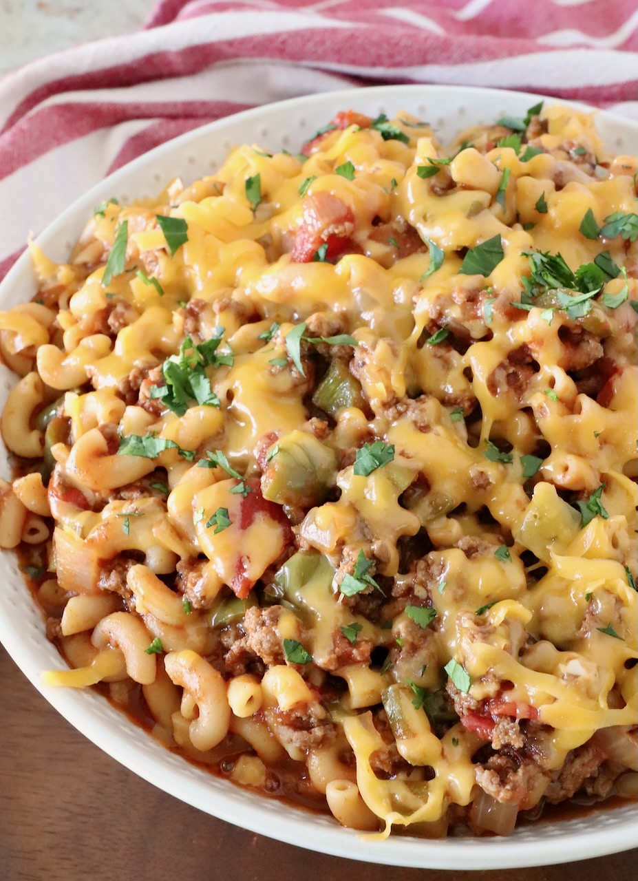 prepared goulash in a bowl topped with cheddar cheese