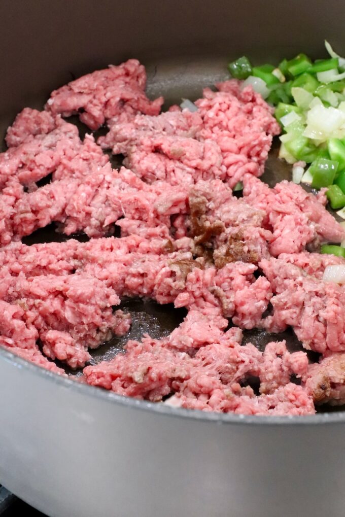 ground beef in a large pot with diced onions and bell peppers