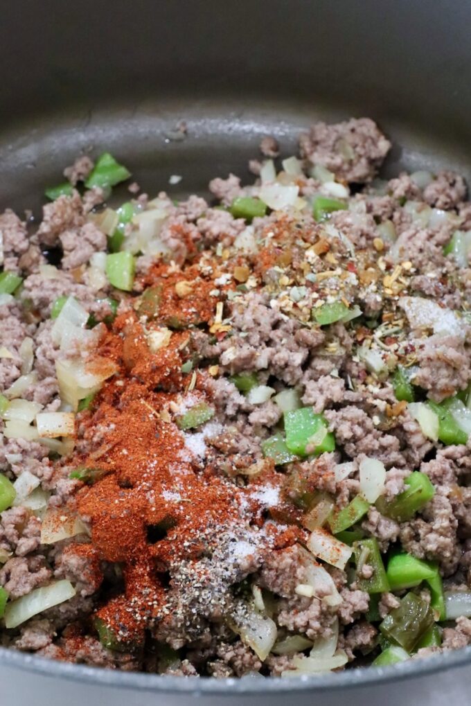 cooked ground beef in a large pot with spices on top