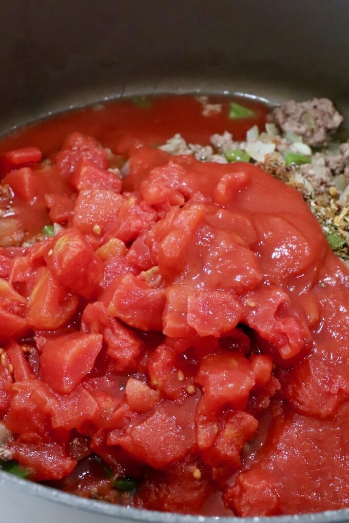 diced tomatoes and tomato sauce in a large pot with cooked, seasoned ground beef