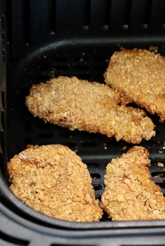 breaded chicken strips in an air fryer basket