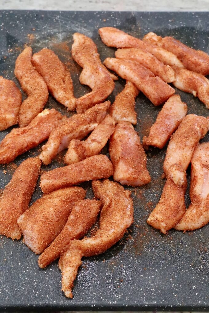 seasoned strips of chicken on a cutting board