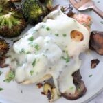 chicken covered in mushrooms and cheese on a plate with broccoli