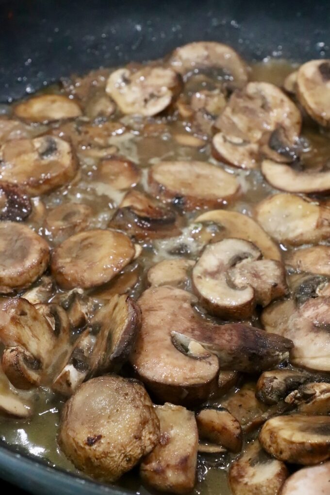 sliced mushrooms cooking in a skillet