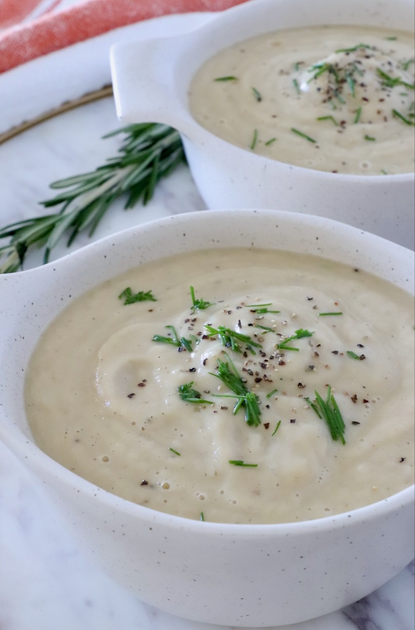 parsnip soup in two bowls topped with chopped chives