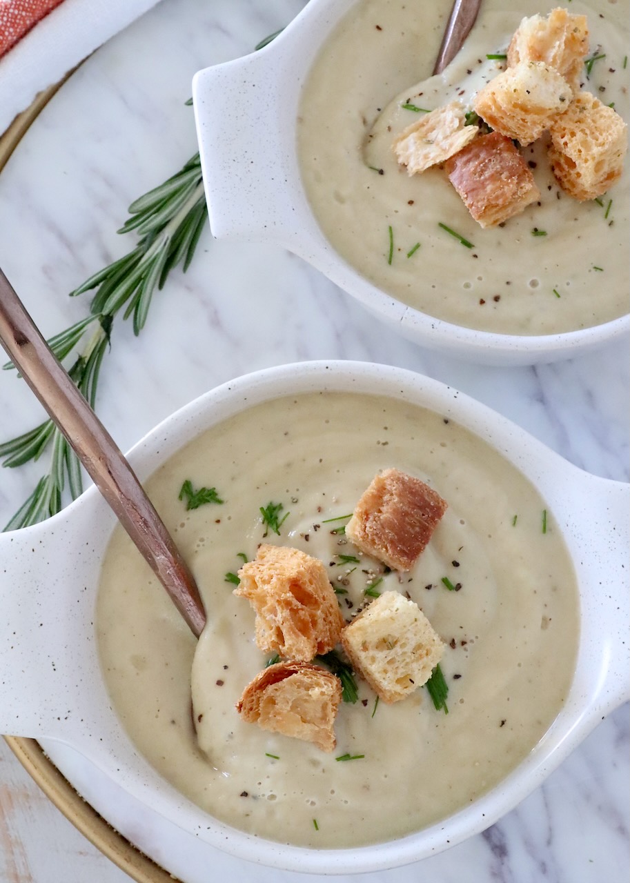 parsnip soup in bowls topped with croutons and chives