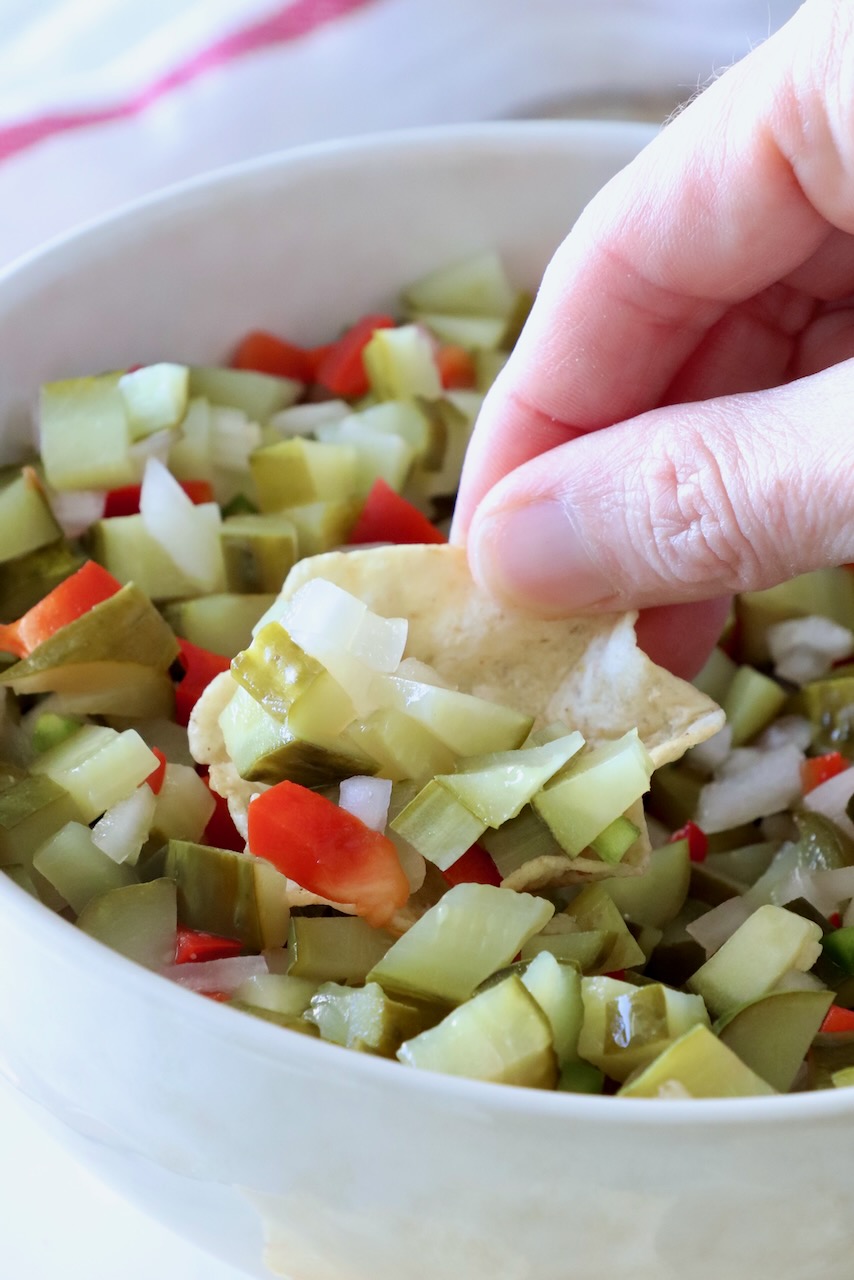 hand holding tortilla chip dipped in pickle de gallo