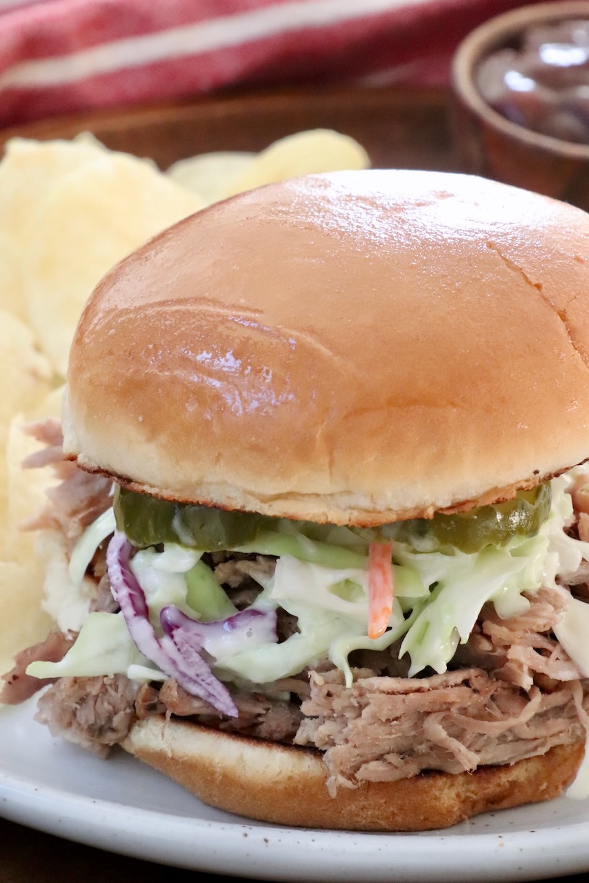 pulled pork sandwich on a plate topped with coleslaw