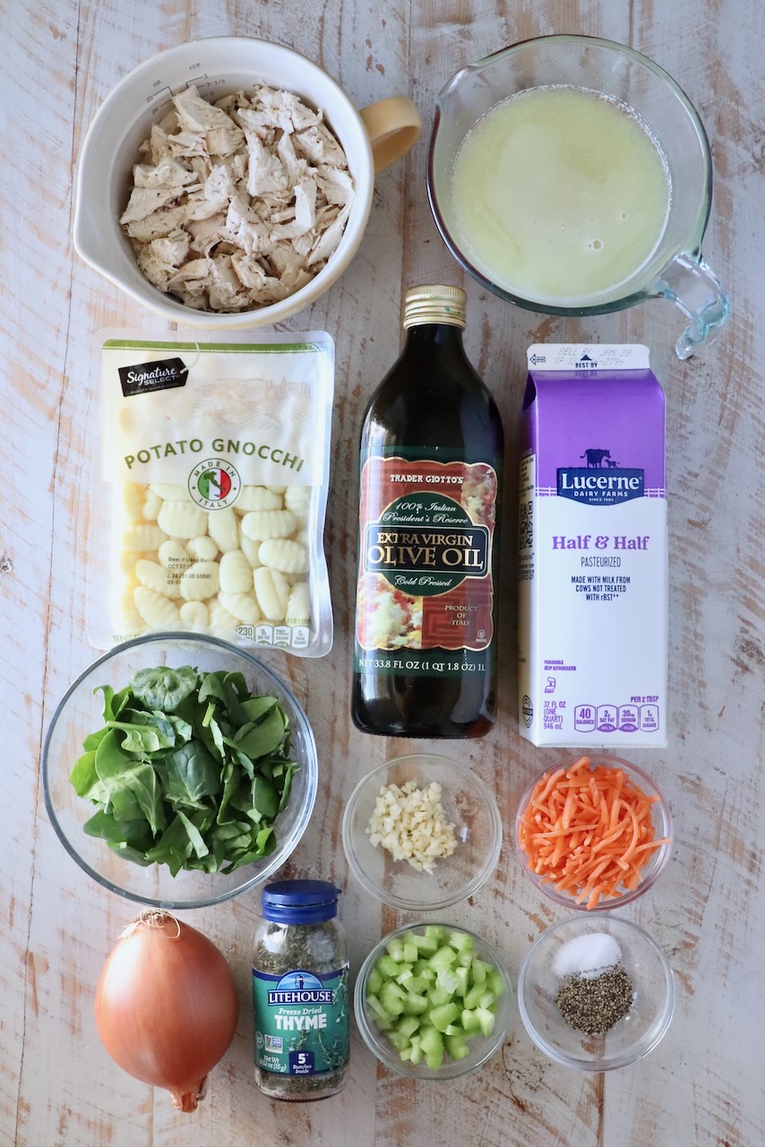 ingredients for chicken gnocchi soup on a white wood board