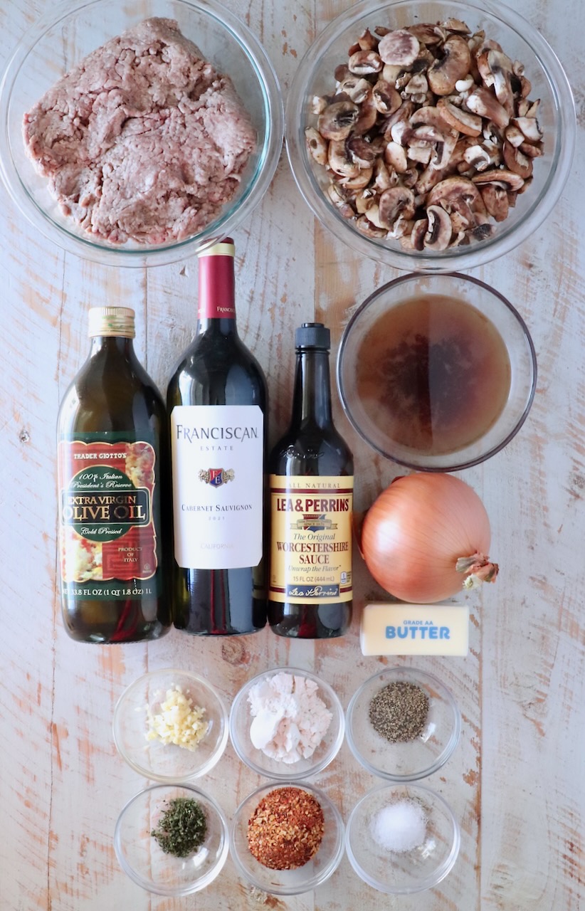 ingredients for chopped steak with red wine gravy on a white wood board