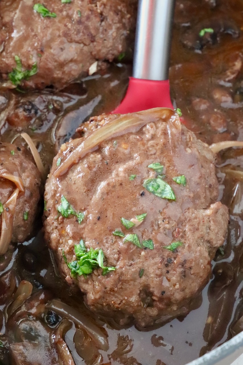 chopped steak in gravy in a pan with a red spatula