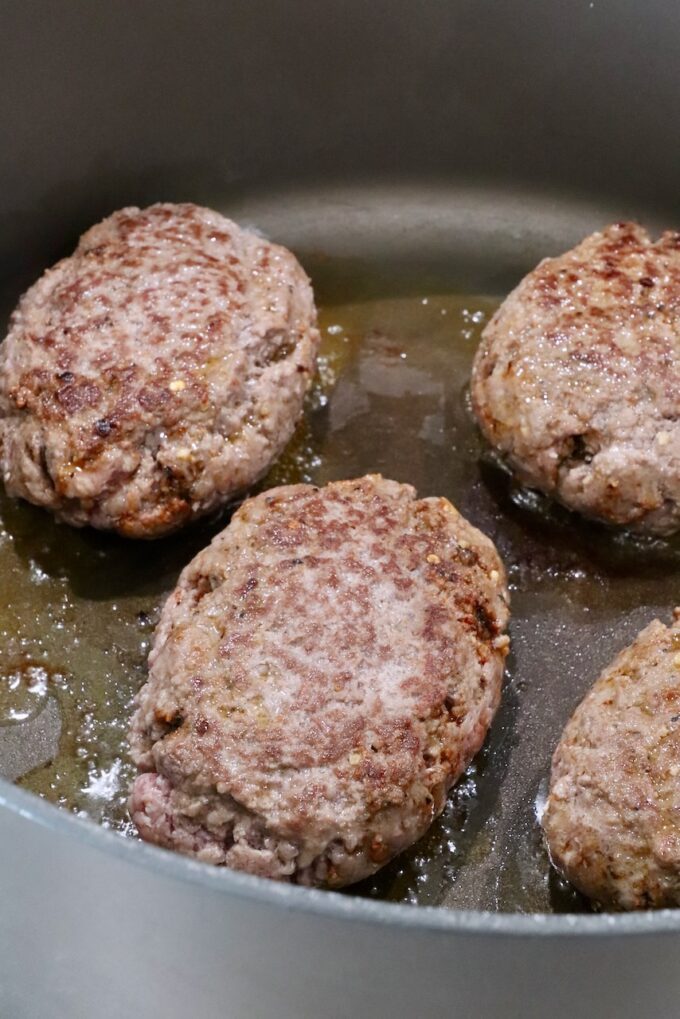 seared ground beef patties in a large dutch oven on the stove