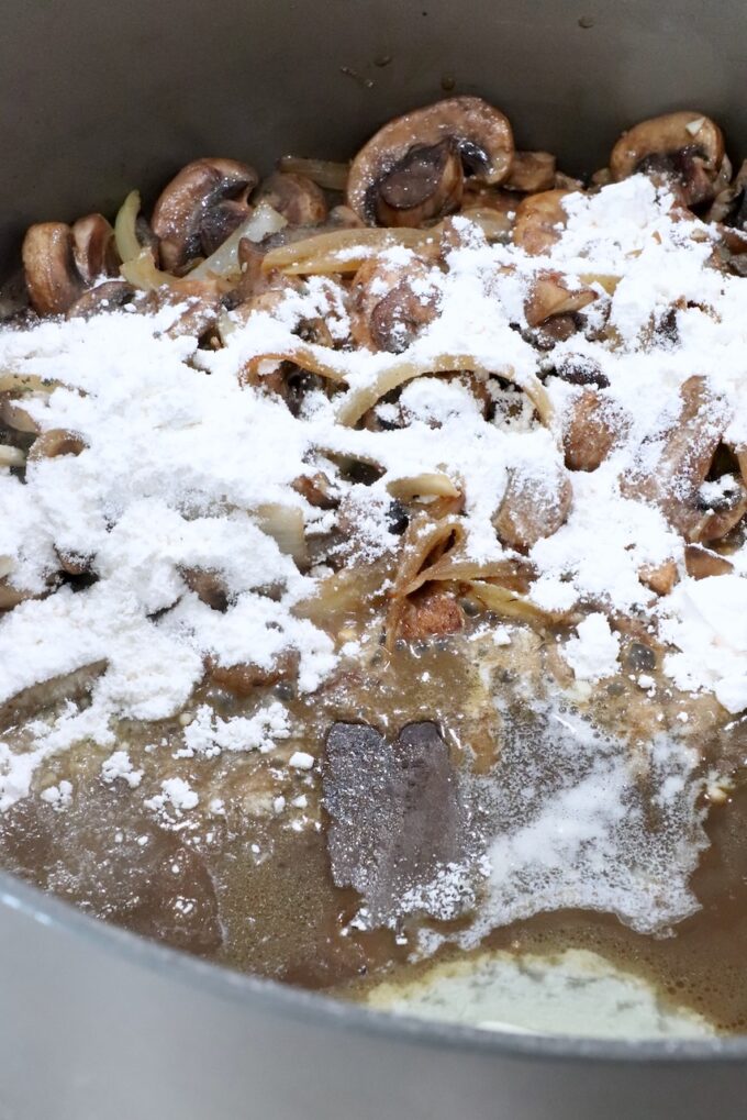 sliced mushrooms and onions in a pot with melted butter and flour