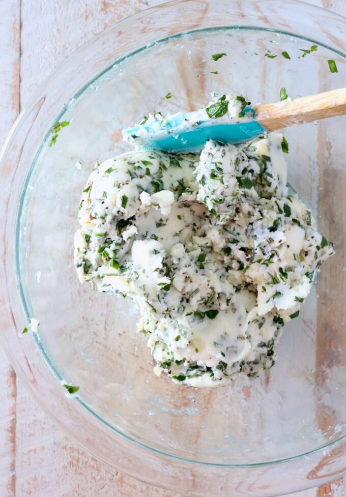 garlic herb compound butter mixed together in a glass bowl with a spatula