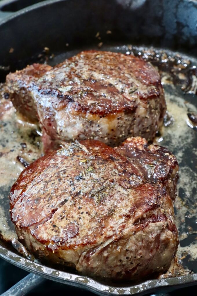 cooked steaks in a skillet with garlic rosemary butter