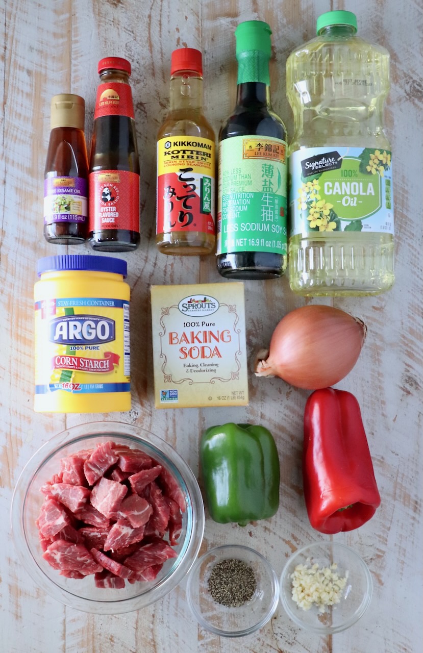 ingredients for pepper steak on a white wood board