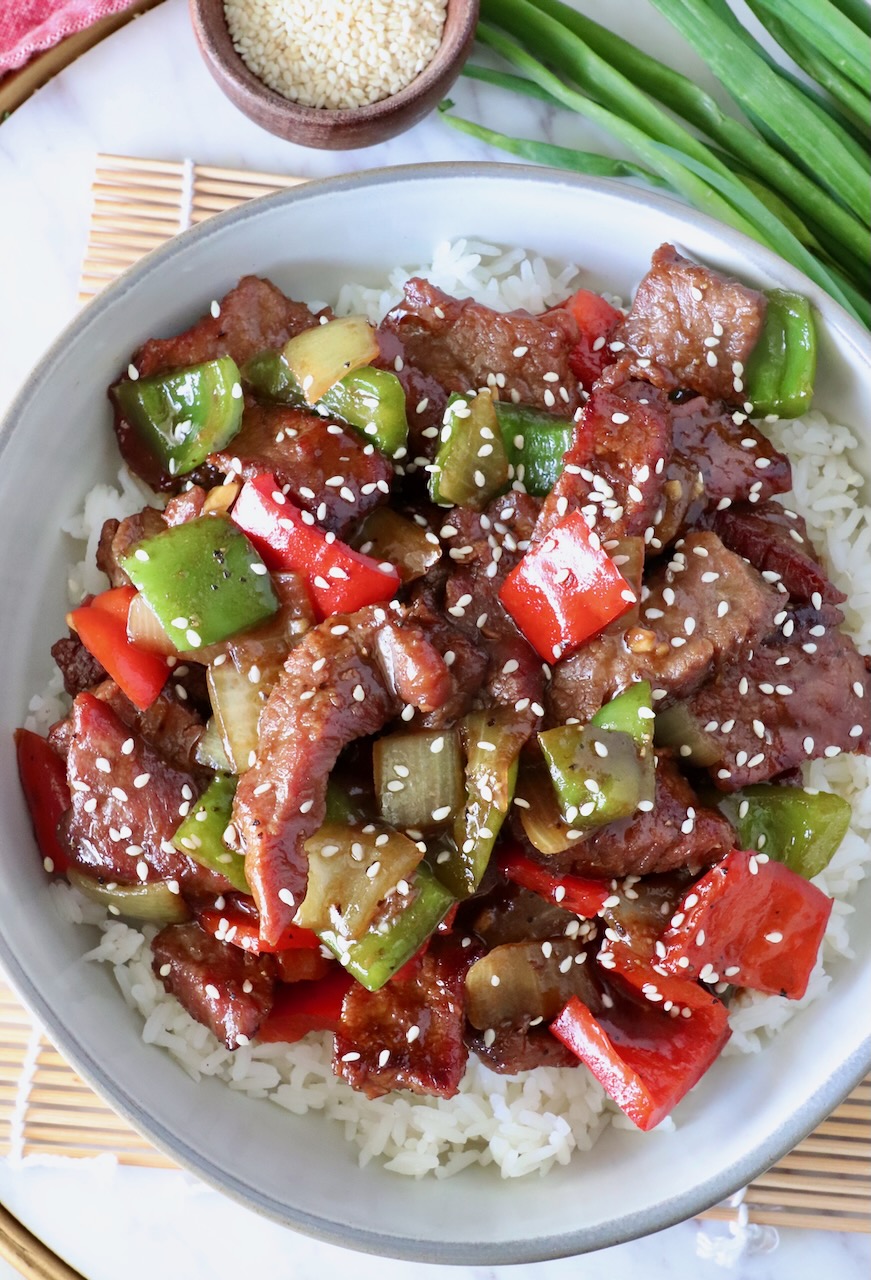 prepared pepper steak on top of cooked white rice in a bowl