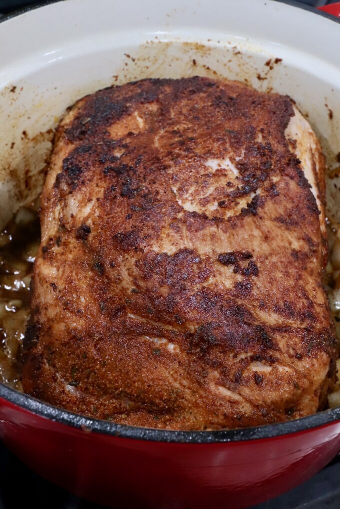 seasoned seared pork shoulder in a large cast iron pot