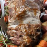 roasted pork on a serving platter with vegetables and rosemary