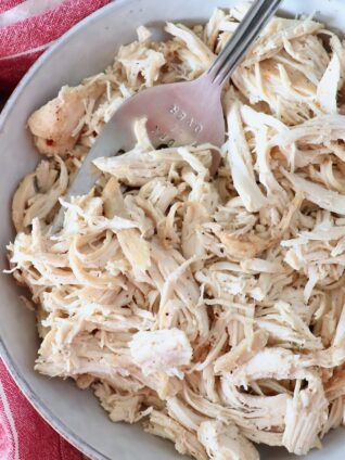 cooked, shredded chicken in a bowl with a large serving fork