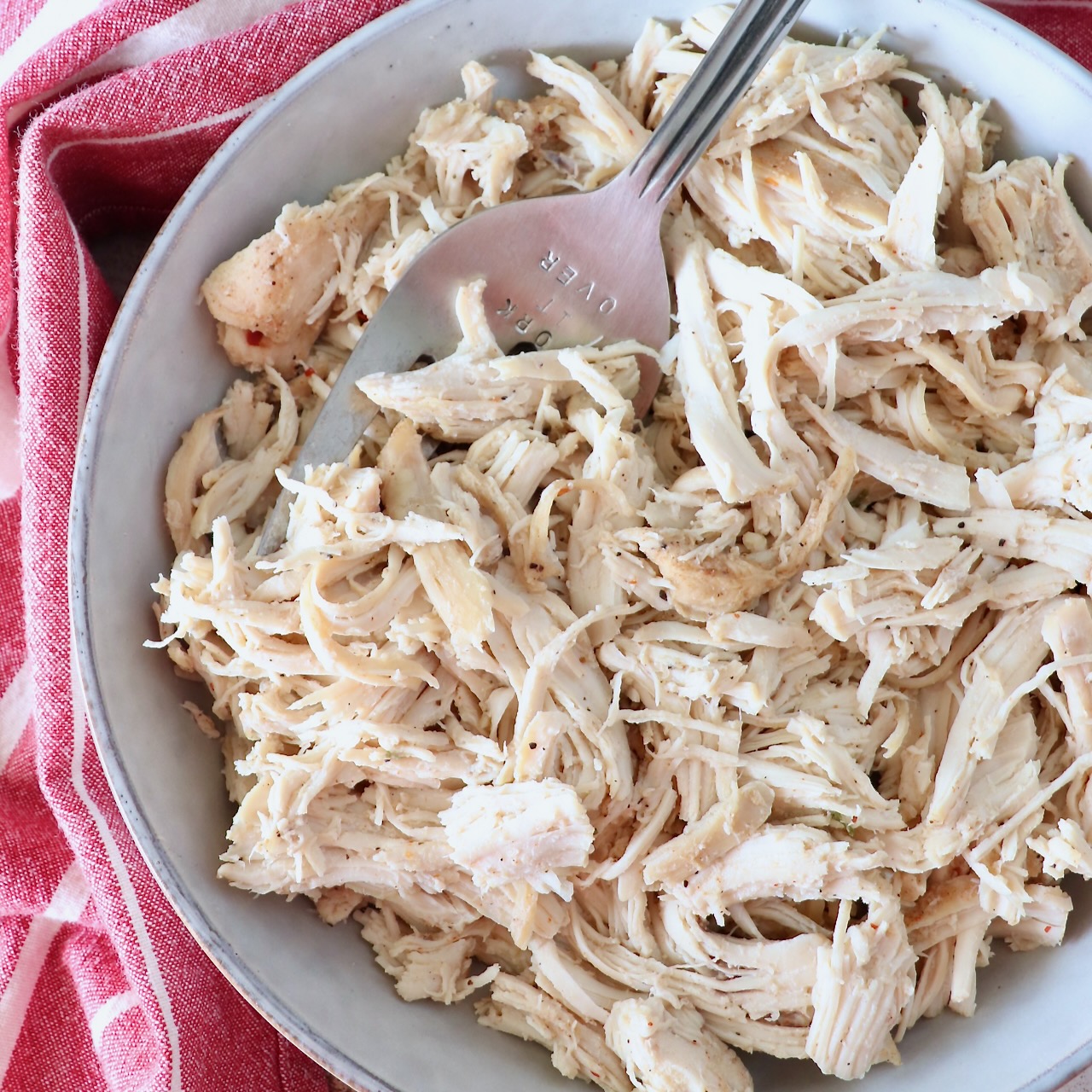 cooked, shredded chicken in a bowl with a large serving fork