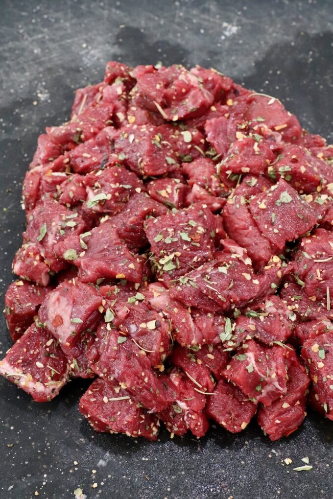 seasoned cubes of steak on a black cutting board