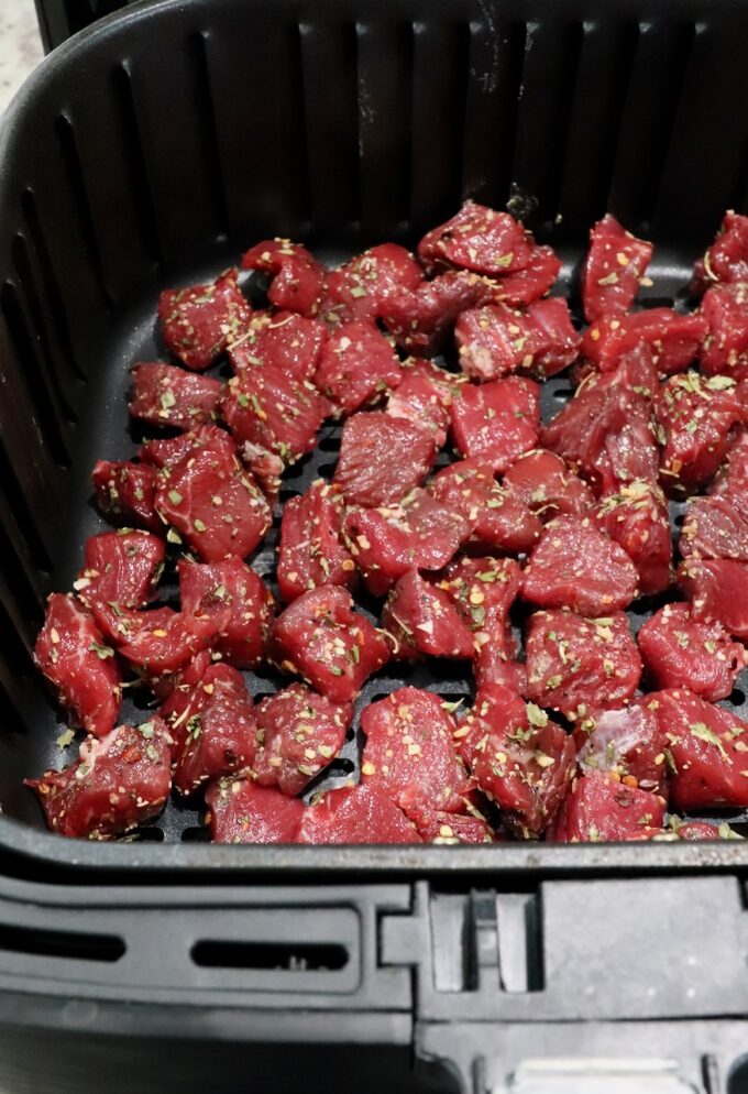 seasoned cubes of steak in an air fryer basket