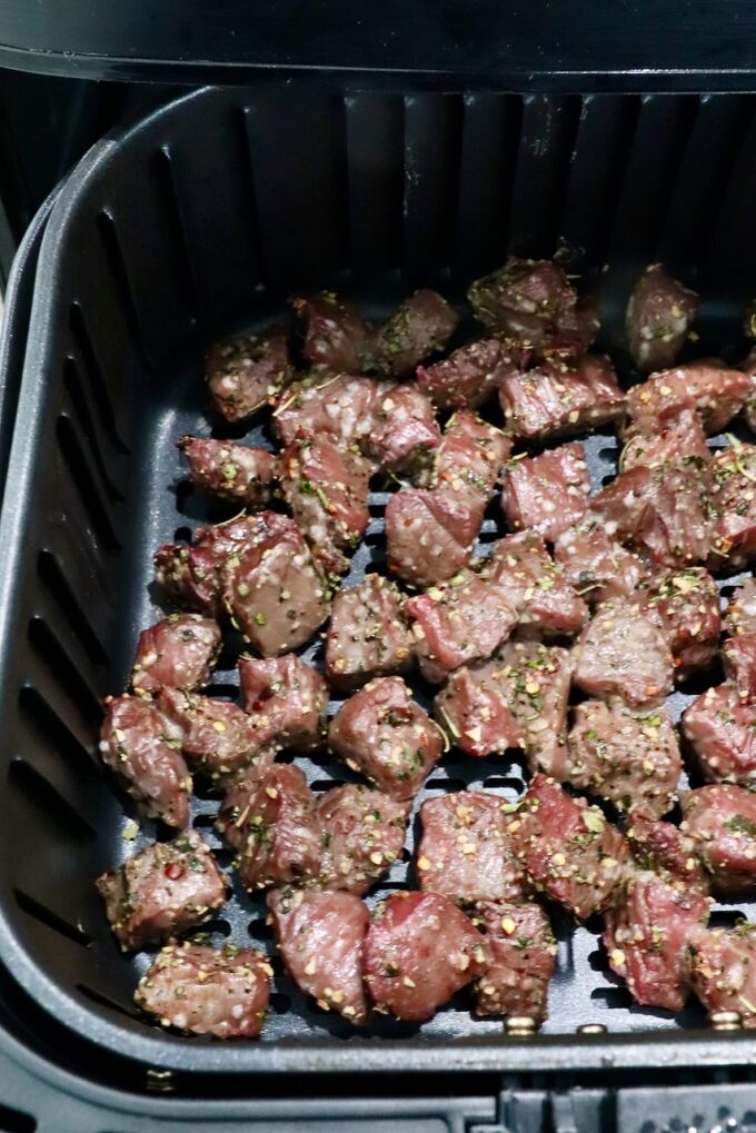 cooked cubes of steak in an air fryer basket