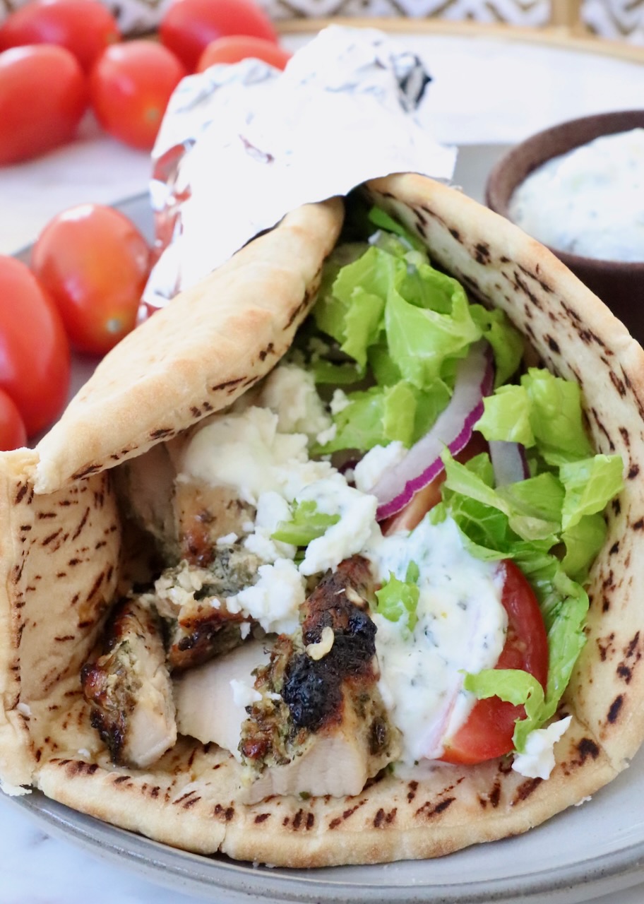 cooked chicken gyro meat in a piece of pita bread with lettuce, tomato and tzatziki sauce