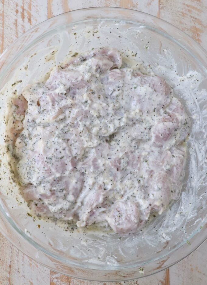 chicken thighs in a seasoned yogurt marinade in a large glass bowl