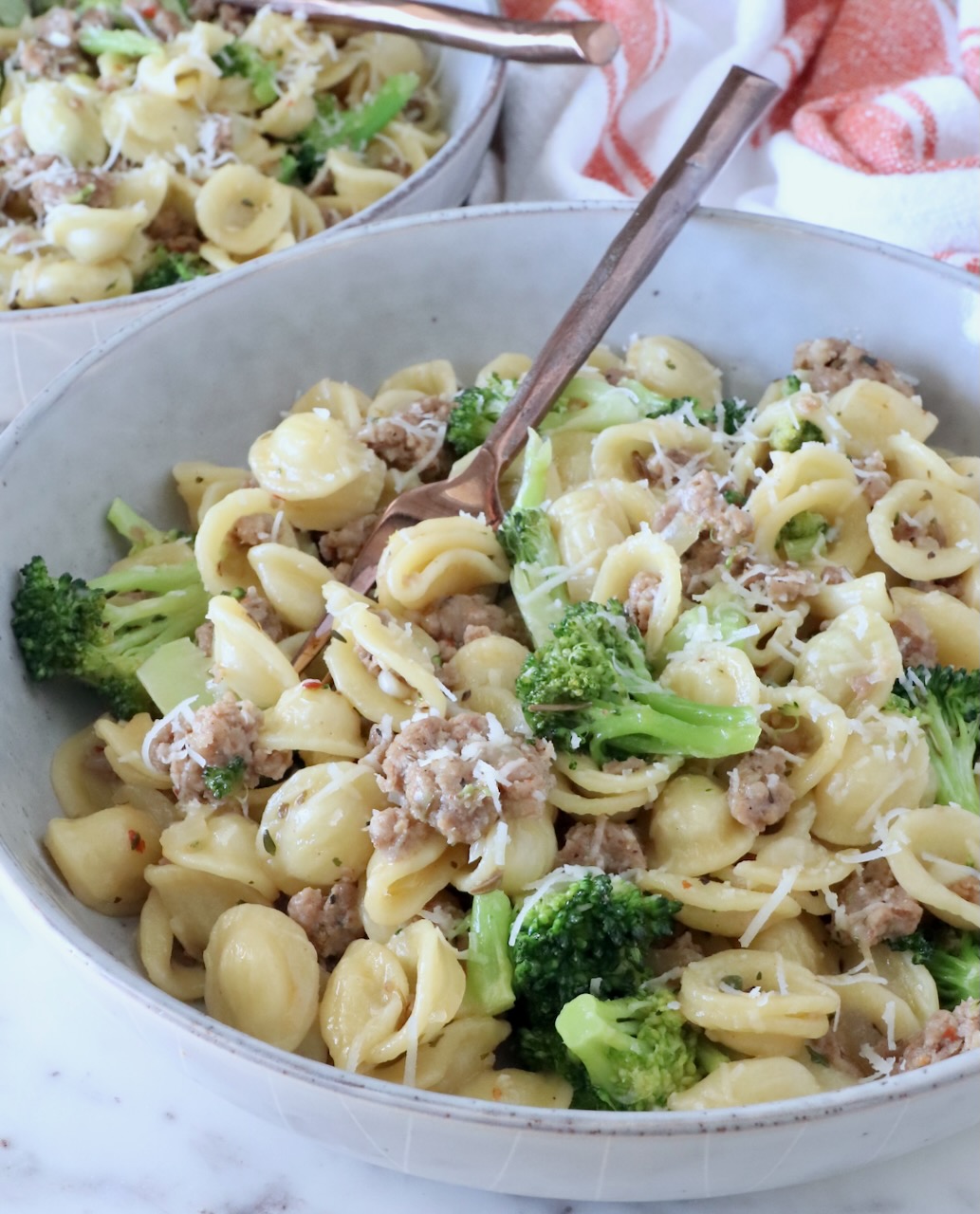 cooked orecchiette pasta with broccoli and cooked sausage in a bowl with a fork