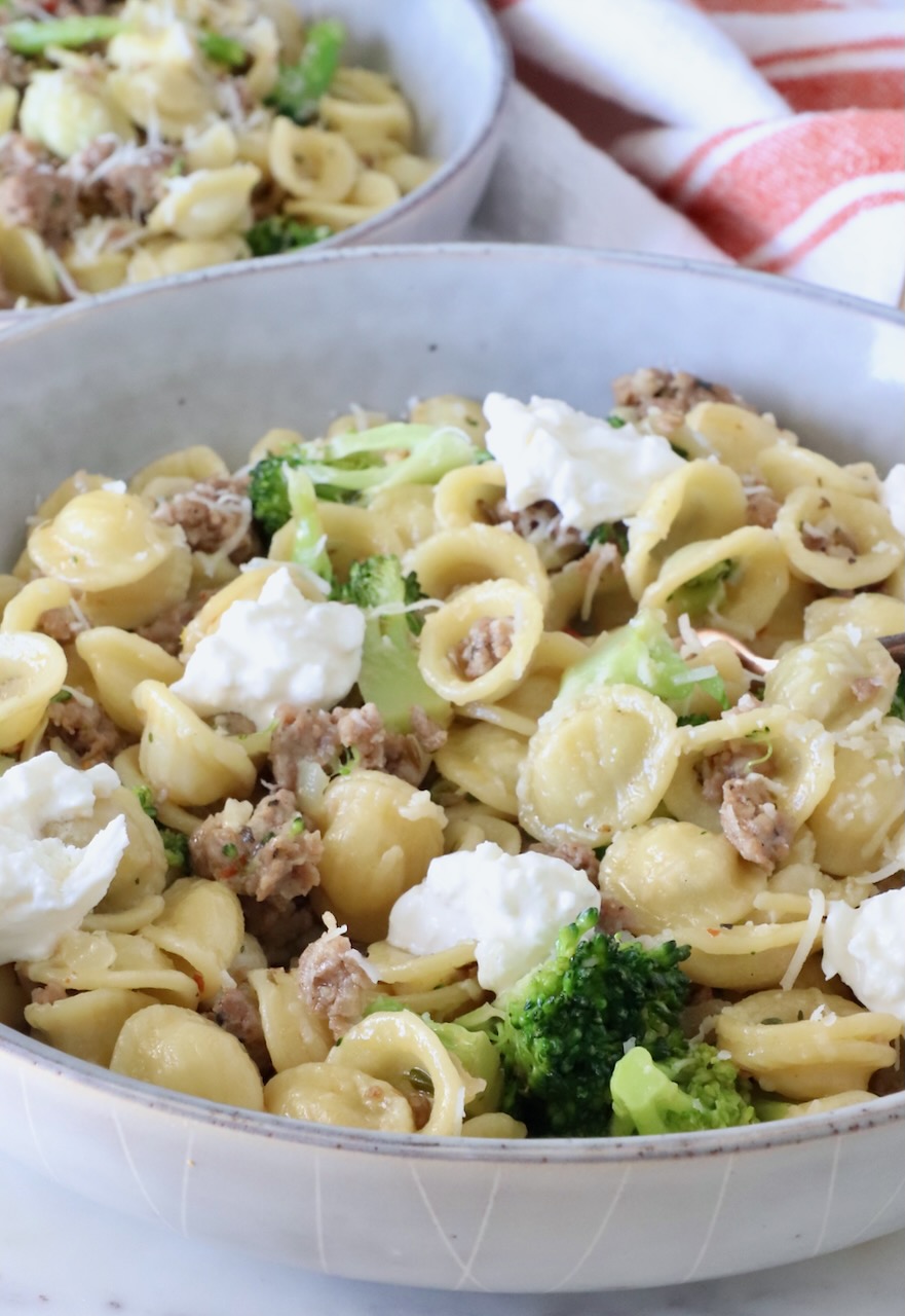 cooked orecchiette pasta with broccoli and sausage in a bowl topped with dollops of burrata cheese