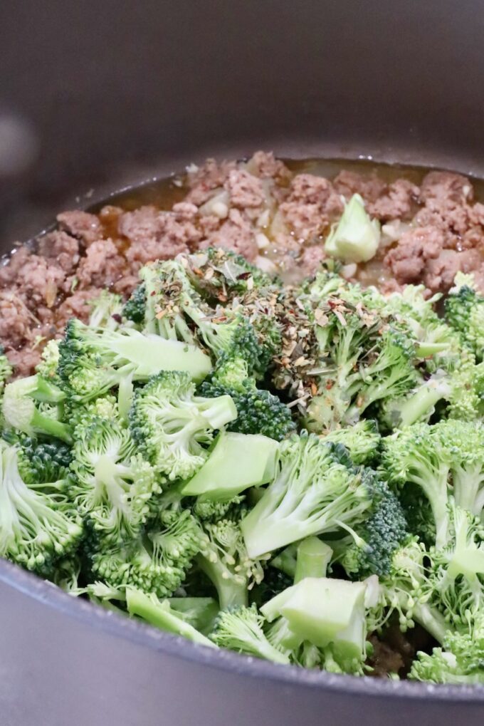 seasoned broccoli and cooked sausage in a large pot