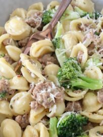 cooked orecchiette pasta with broccoli and cooked sausage in a bowl with a fork